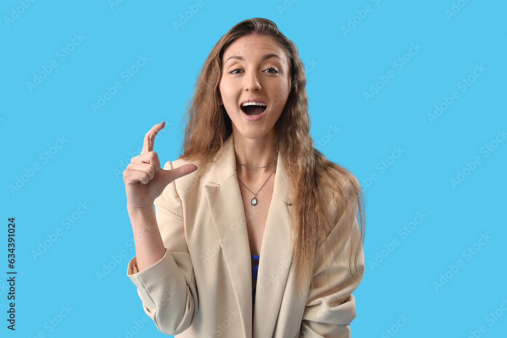 Happy young woman in jacket holding something on blue background