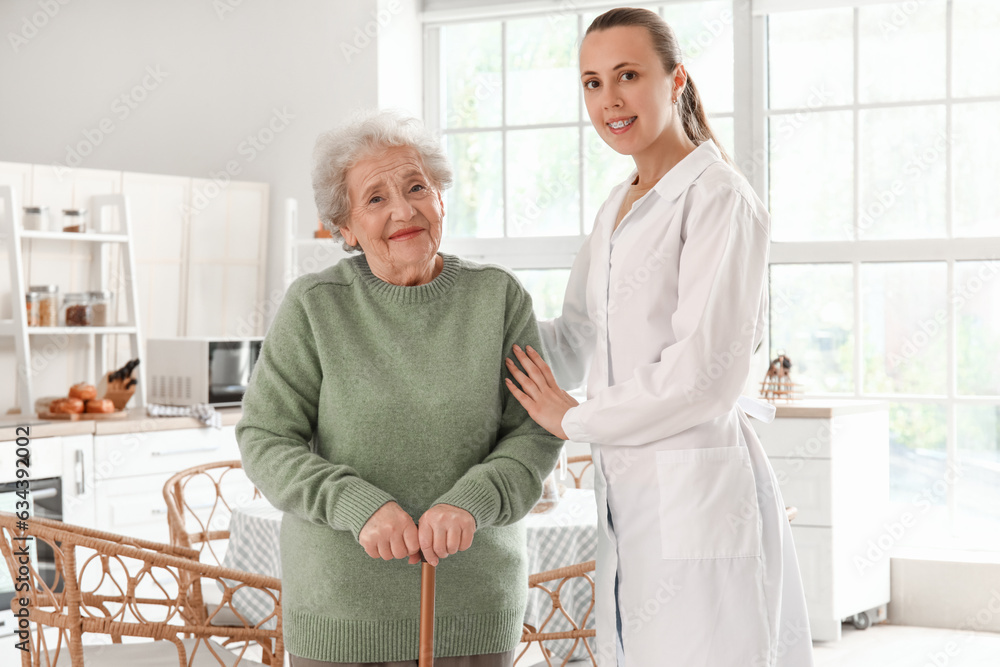 Senior woman with walking stick and female doctor in kitchen