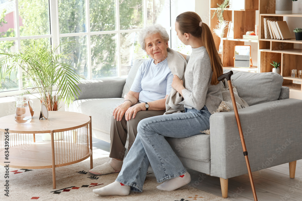 Senior woman with her granddaughter sitting on sofa at home