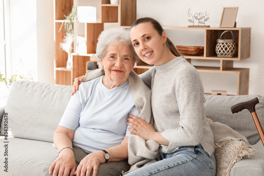 Senior woman with her granddaughter sitting on sofa at home