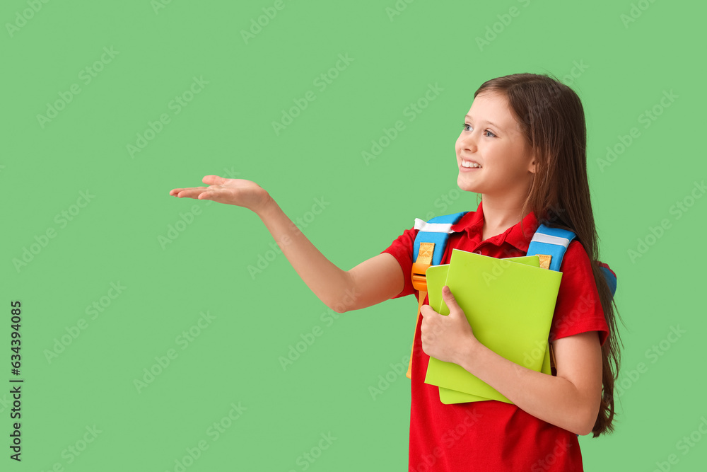 Little schoolgirl with copybooks showing something on green background