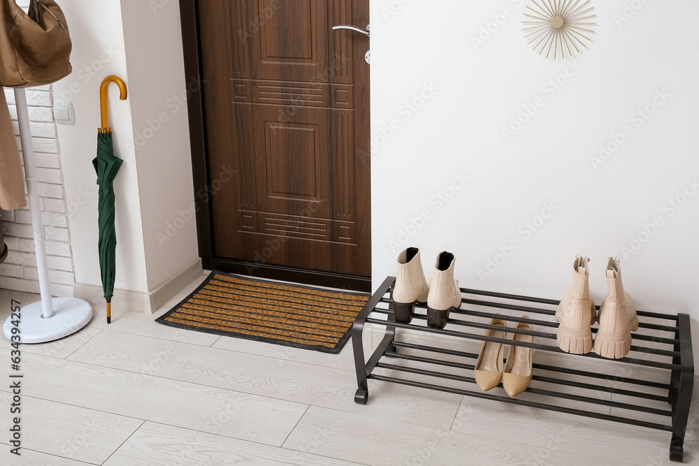 Door and stand with shoes in interior of light hall