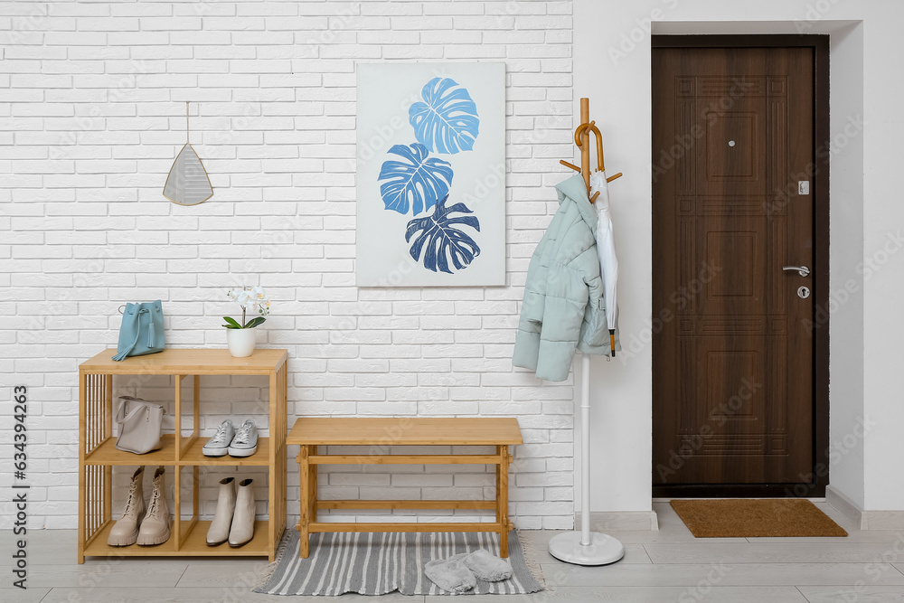 Interior of light hall with door, picture and shelving unit