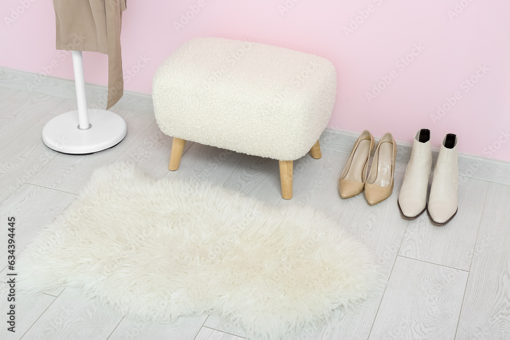 Modern bench, rack with coat and shoes near pink wall in hall