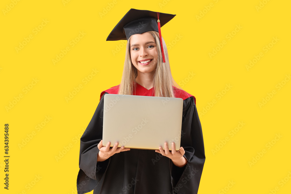 Female graduate student with laptop on yellow background