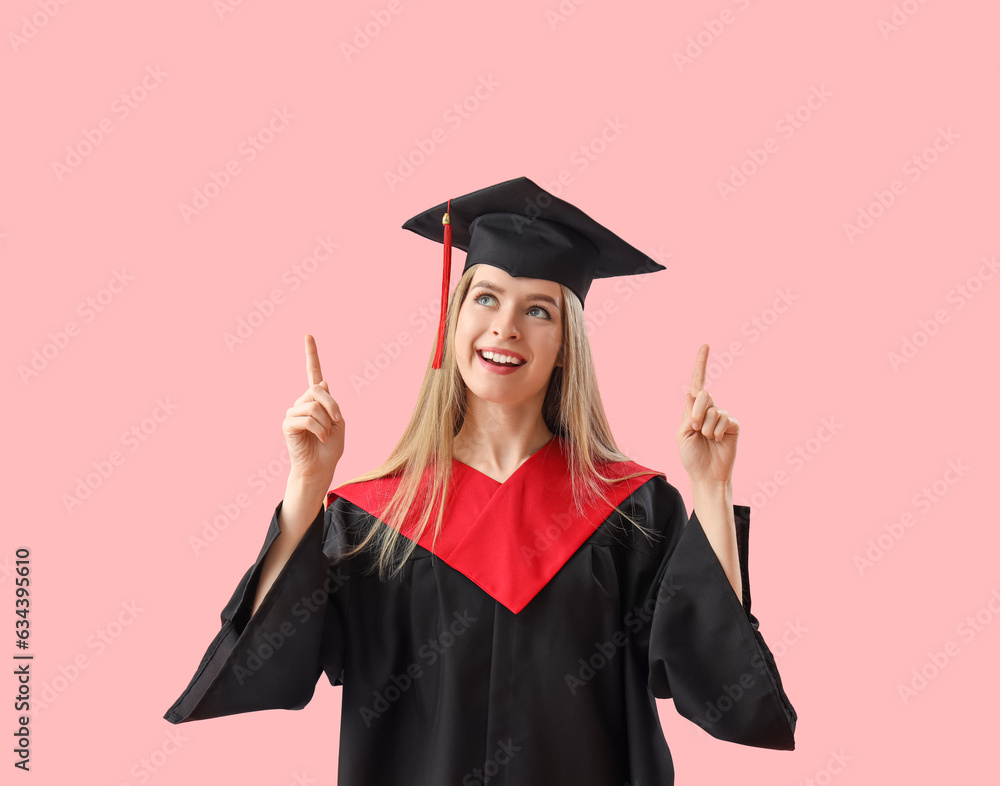 Female graduate student pointing at something on pink background