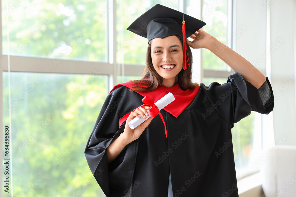 Female graduate student with diploma near window in room