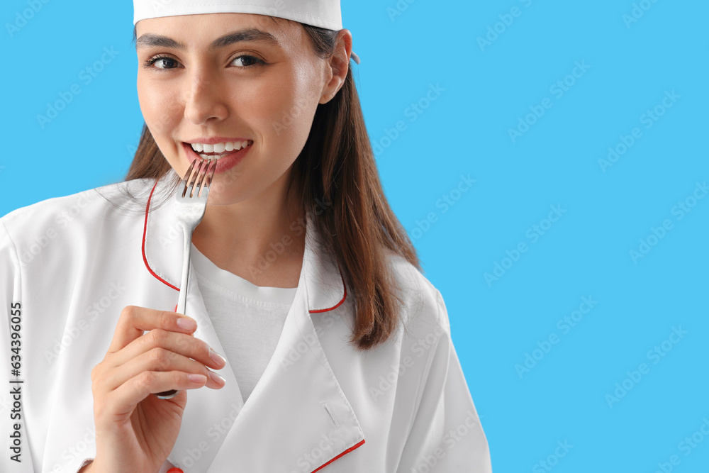 Female chef with fork on blue background, closeup