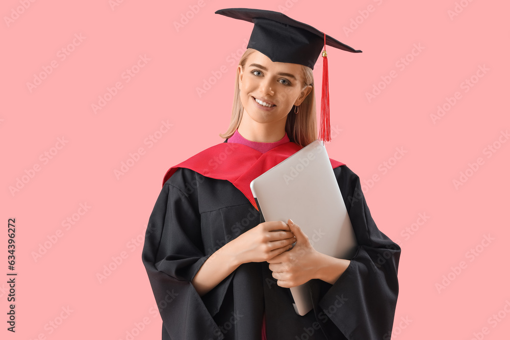 Female graduate student with laptop on pink background