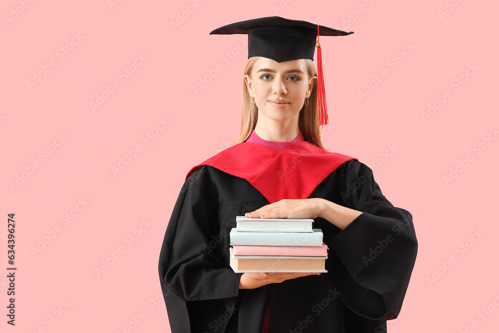 Female graduate student with books on pink background