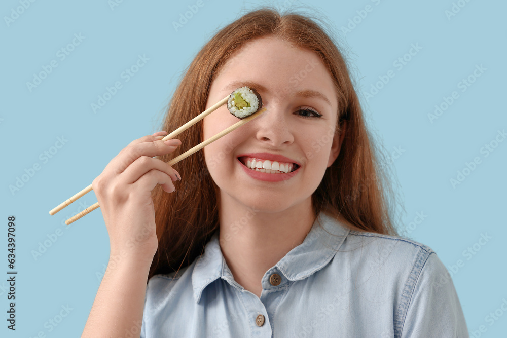 Young woman with tasty sushi roll on blue background, closeup