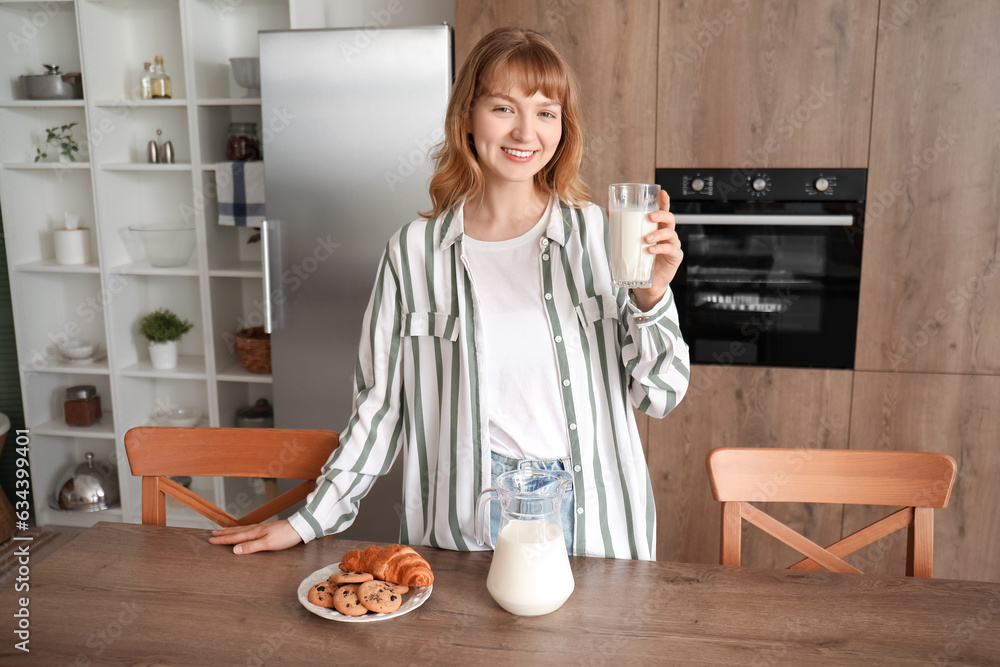 Young woman with glass of milk in kitchen