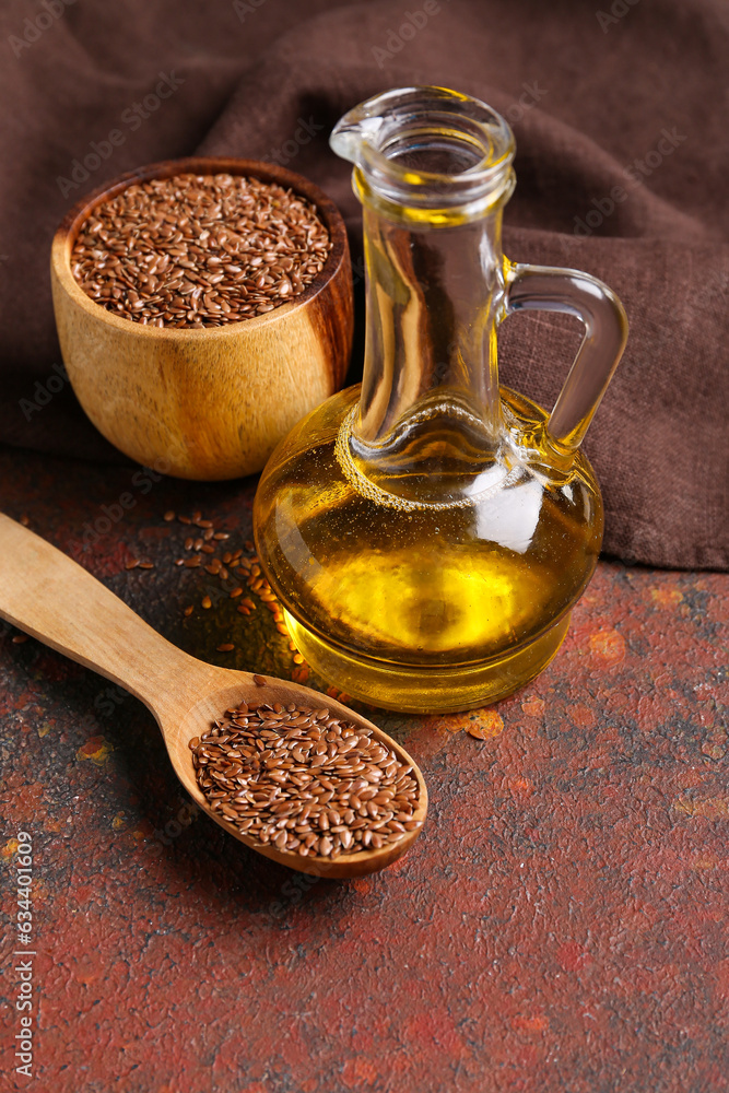 Decanter of flax oil and wooden bowl with seeds on dark background