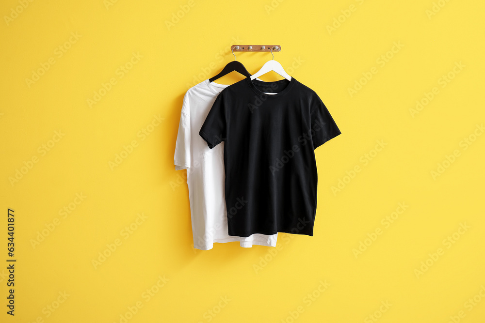 Stylish t-shirts hanging on yellow background