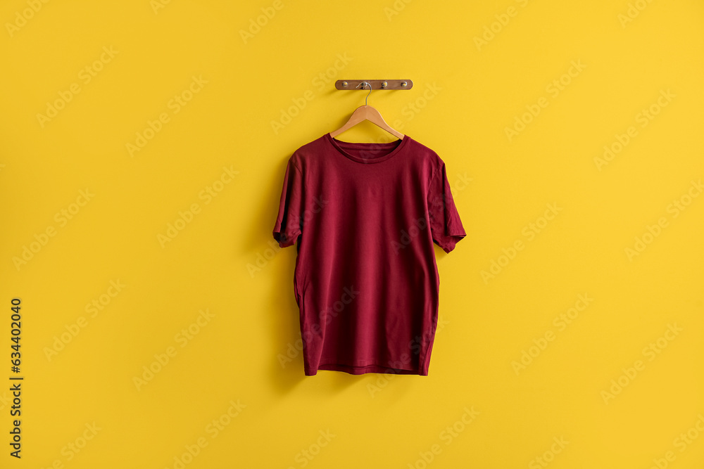 Stylish red t-shirt hanging on yellow background