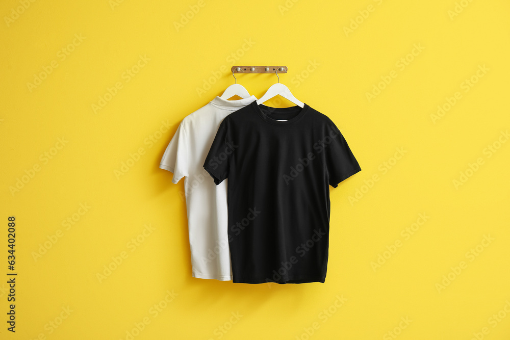 Stylish t-shirts hanging on yellow background