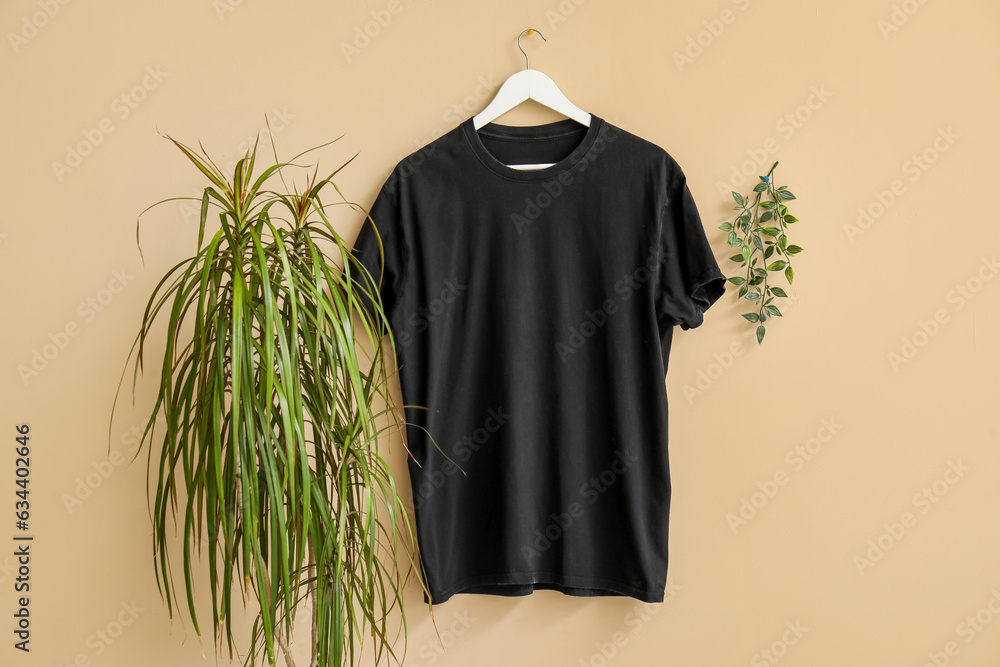 Stylish black t-shirt hanging on beige background