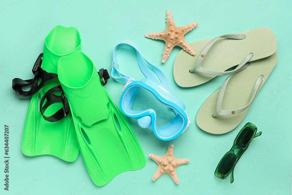 Swimming mask, flip flops, sunglasses, flippers and starfish on turquoise background