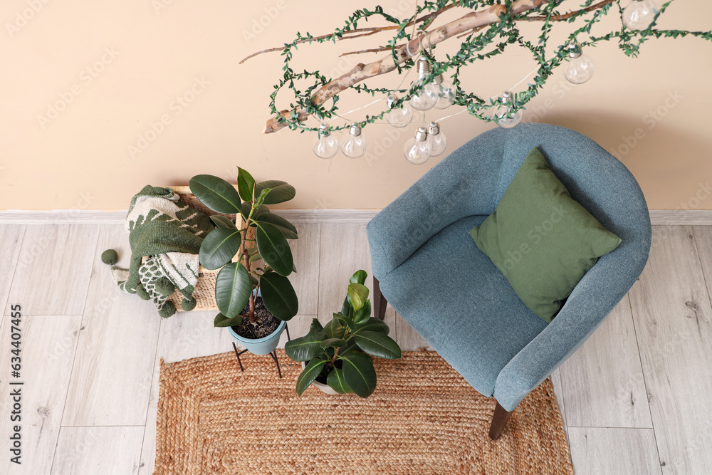 Stylish blue armchair and houseplants near beige wall