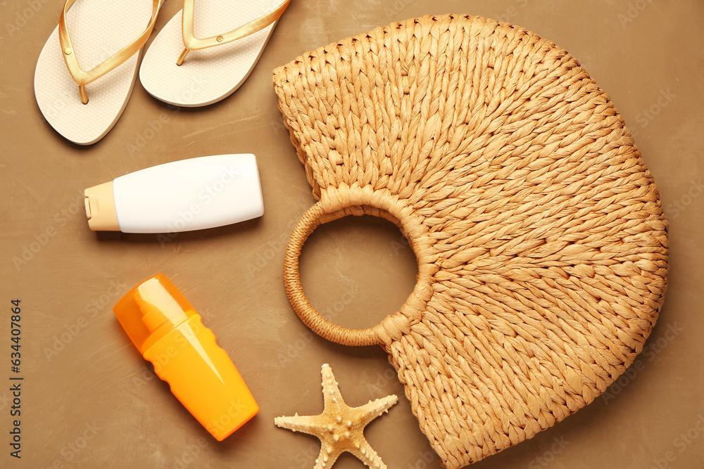 Bottles of sunscreen cream with beach accessories on brown background