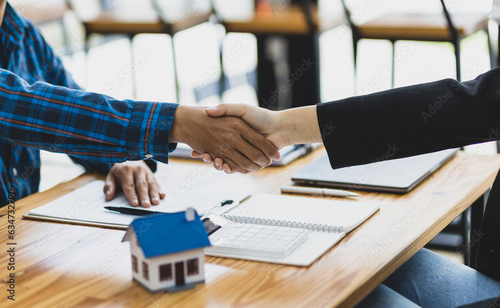 Businessman and real estate agent shaking hands after negotiating home purchase agreement.