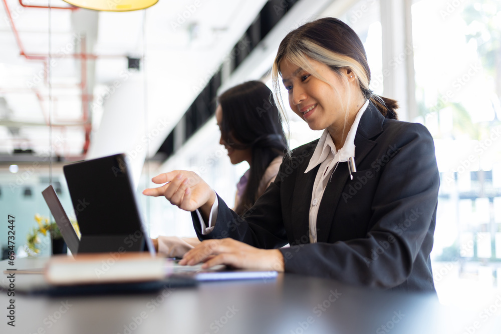 Businesswoman secretary colleague working with laptop in office. Two receptionists work at the count