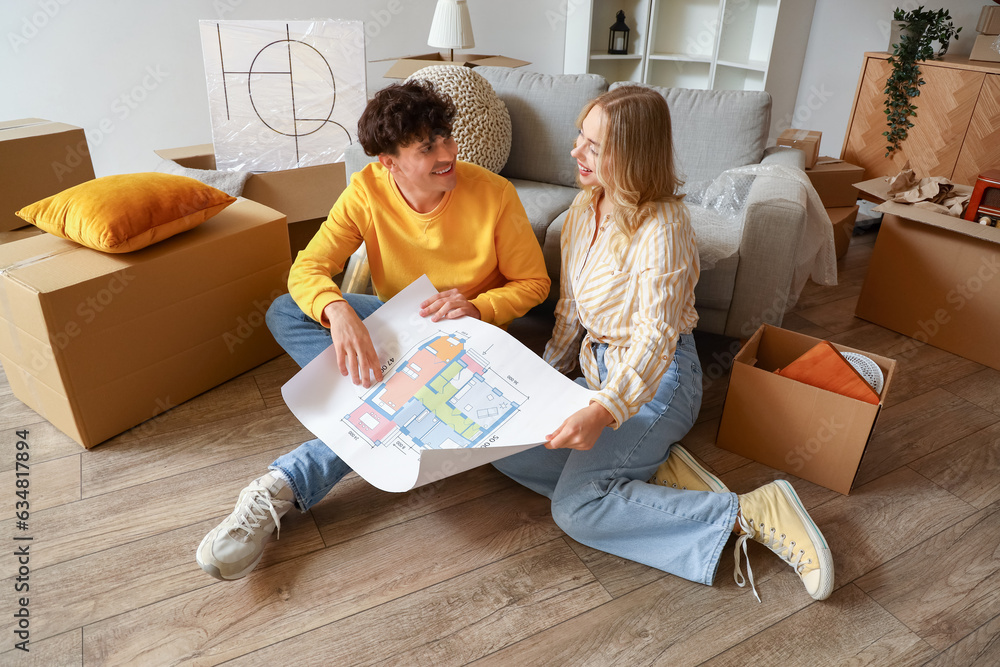 Young couple with house plan sitting in room on moving day