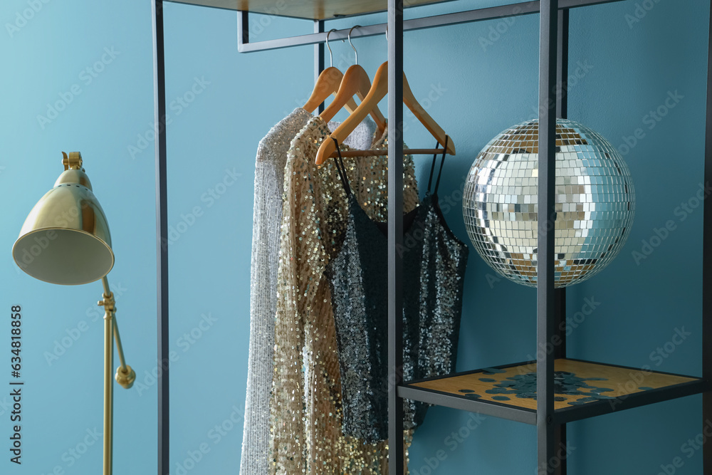 Shelving unit with clothes and disco ball near blue wall in room