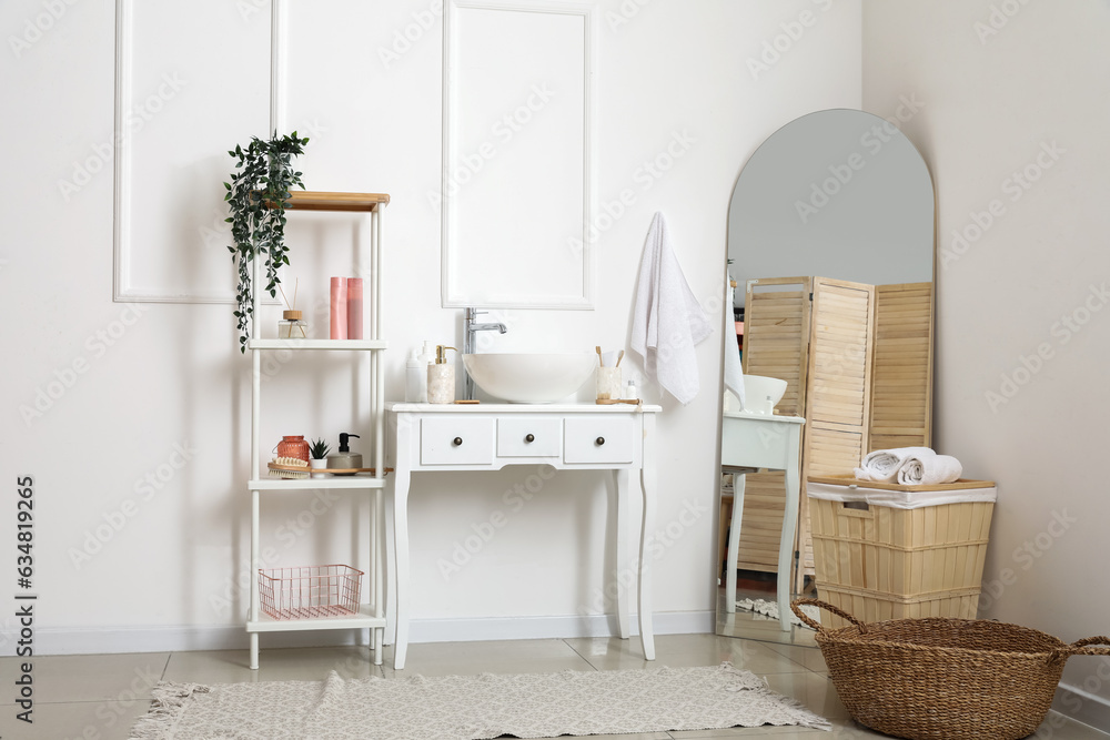 Table with sink bowl, shelving unit and mirror in interior of bathroom