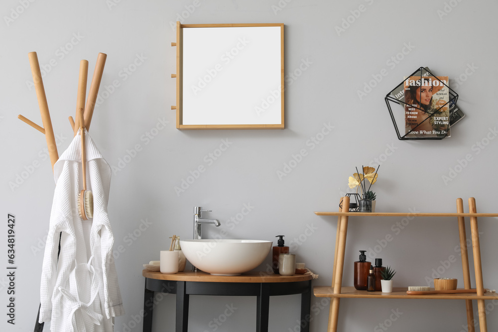 Interior of bathroom with shelving unit, sink bowl and bath accessories on table