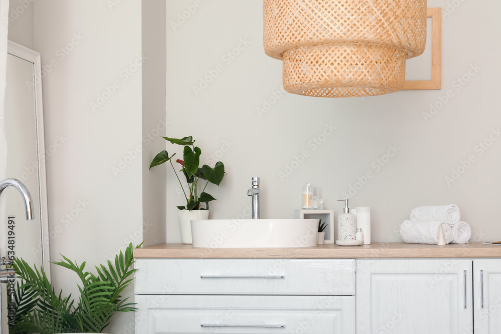 Sink bowl and bath accessories on white counters in bathroom