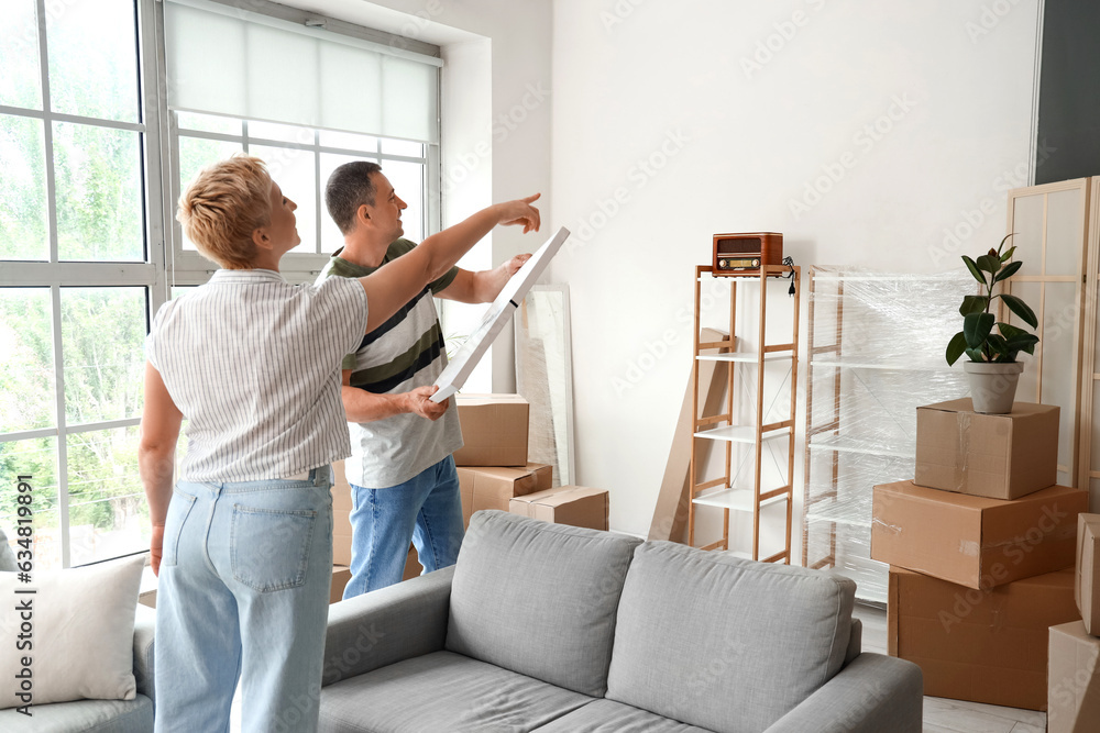 Mature couple planning to hang poster in room on moving day