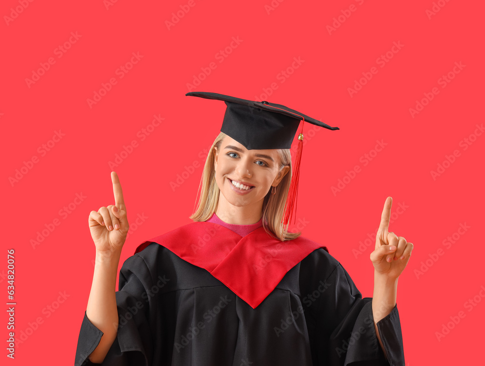 Female graduate student pointing at something on red background