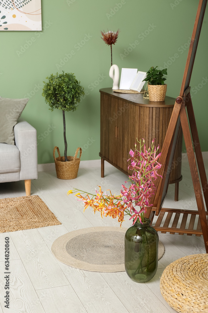 Modern living room interior with wooden cabinet, mirror and vase of flowers