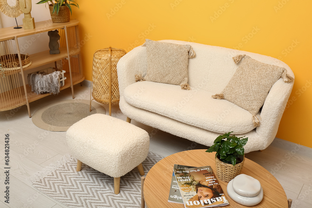 Modern living room interior with comfortable white sofa, ottoman and wooden coffee table