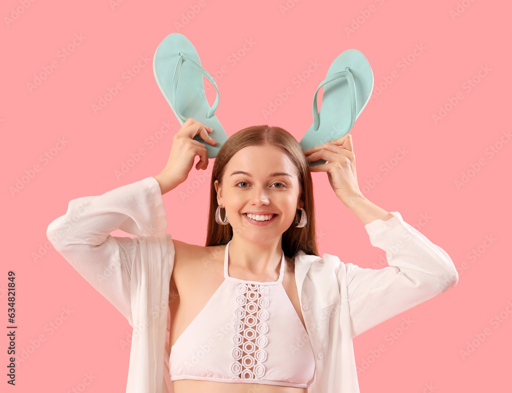 Funny young woman with flip-flops on pink background