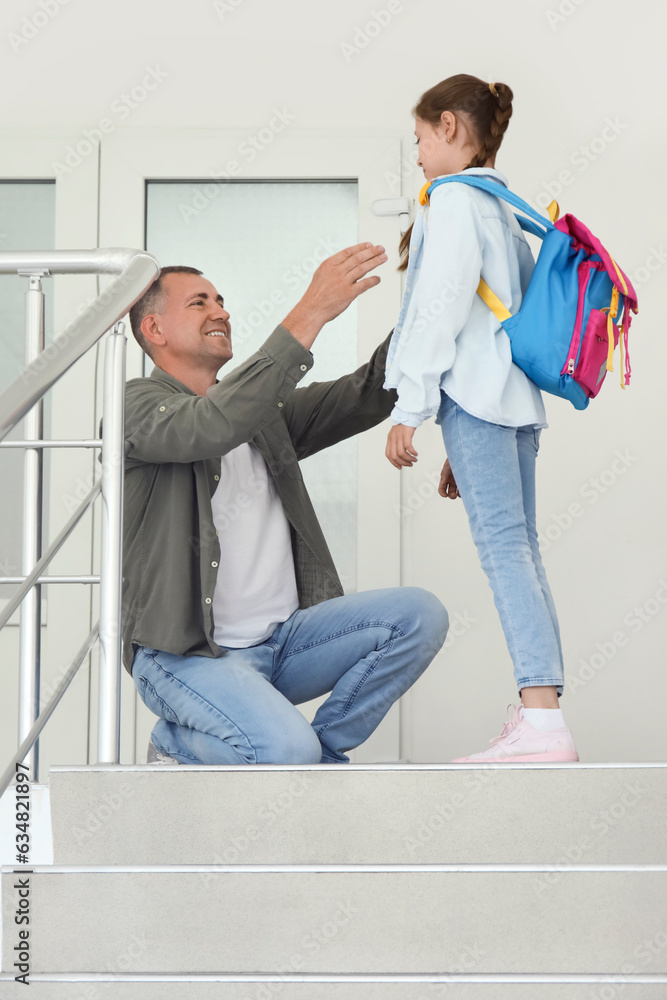 Father walking his little daughter to school in stairway