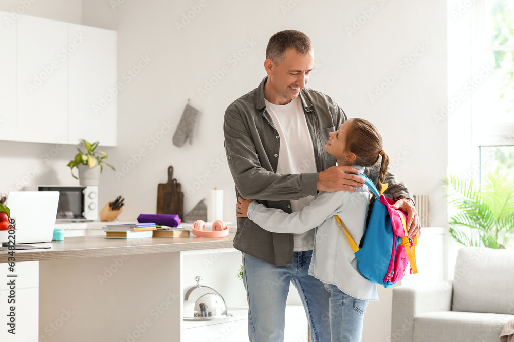 Father hugging his little daughter before going to school in kitchen