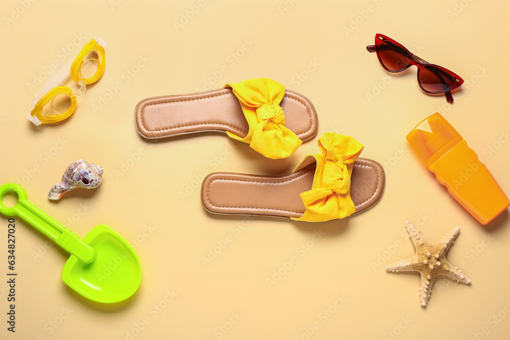 Female stylish flip flops with sunglasses and sunscreen cream on yellow background