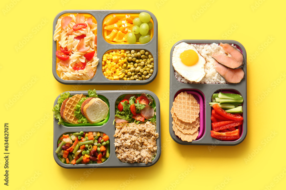 Lunchboxes with different delicious food on yellow background