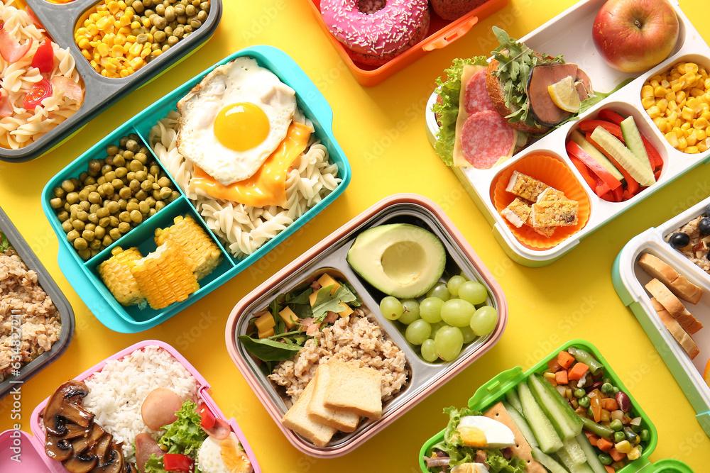 Many lunchboxes with different delicious food on yellow background