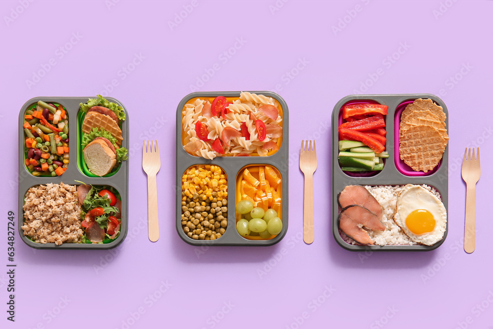 Lunchboxes with different delicious food on lilac background