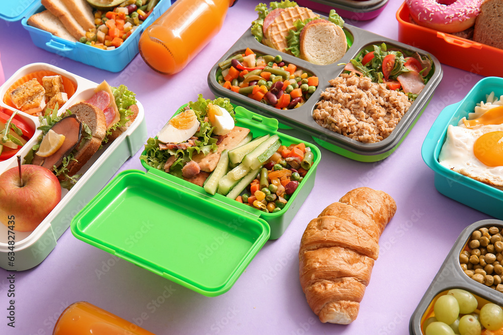 Many lunchboxes with different delicious food on lilac background