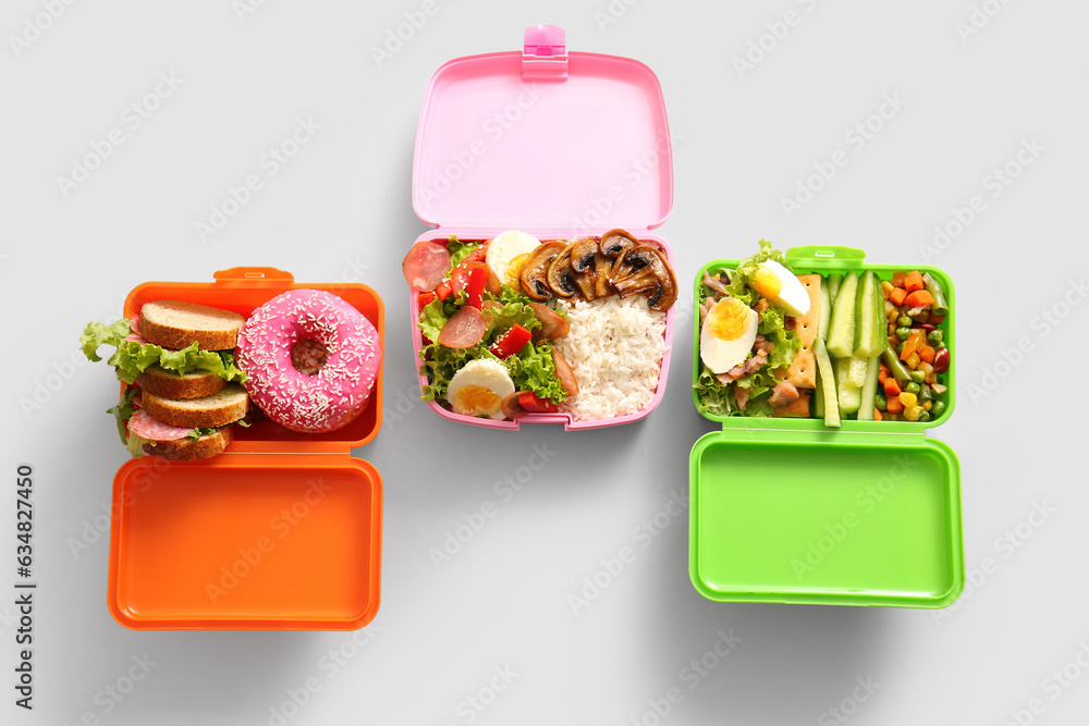 Lunchboxes with different delicious food on grey background