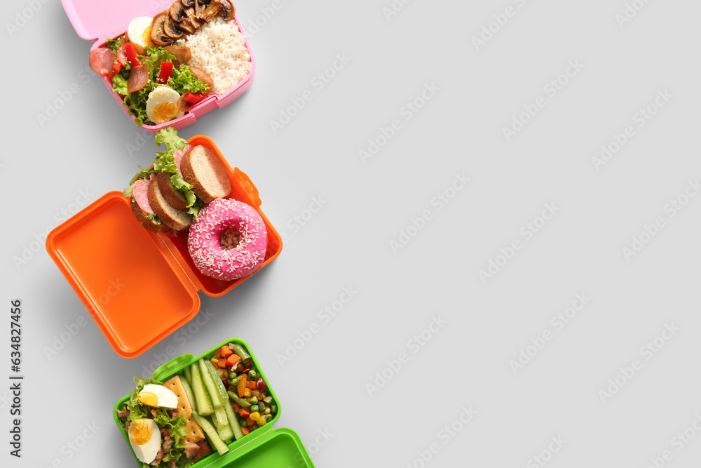 Lunchboxes with different delicious food on grey background