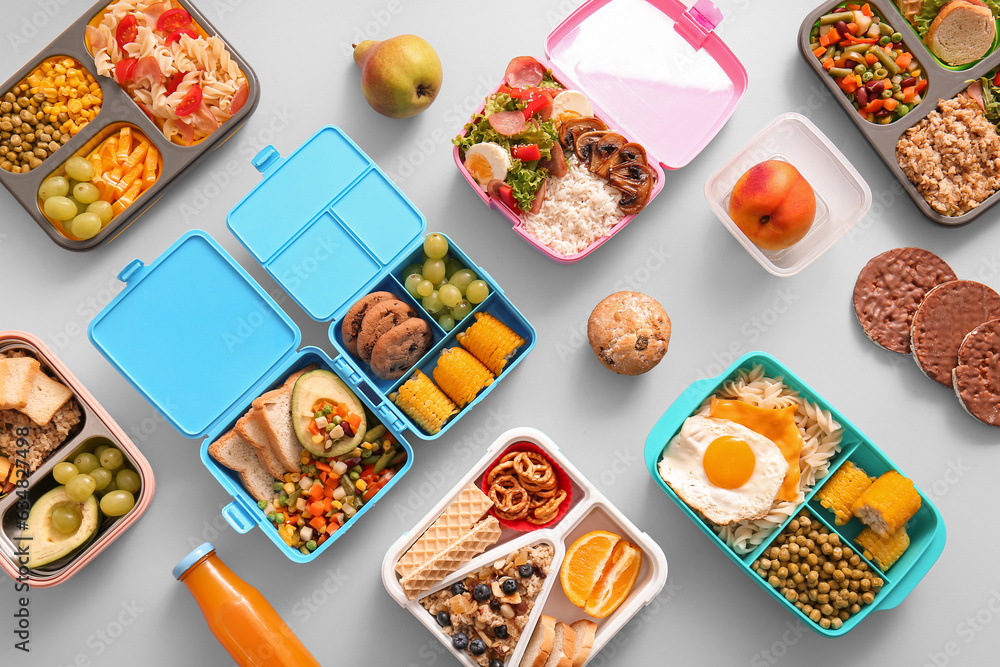 Many lunchboxes with different delicious food on grey background