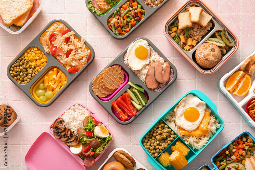 Many lunchboxes with different delicious food on pink tile background