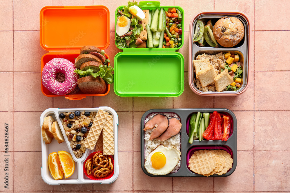 Lunchboxes with different delicious food on pink tile background