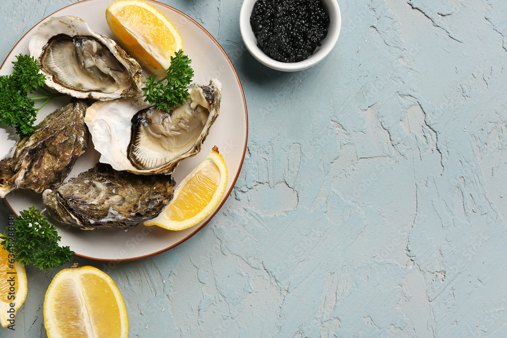 Plate of tasty oysters with lemon and black caviar on grey background