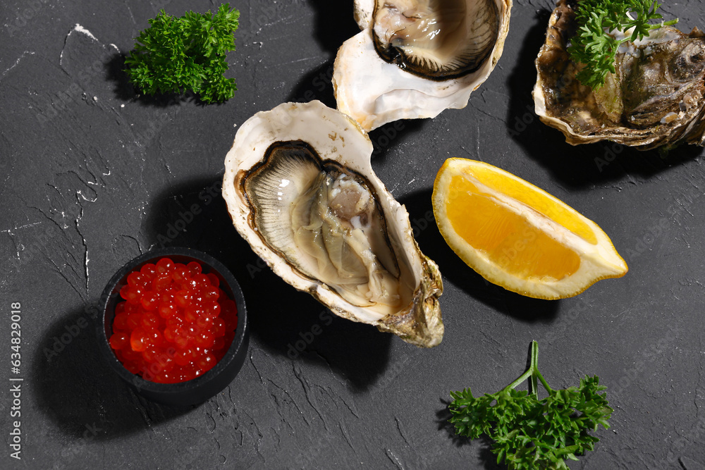 Tasty oysters with lemon and red caviar on black background